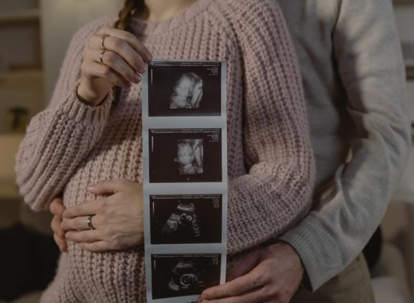 Expectant couple indoors holding ultrasound, symbolizing new life and family bonds.